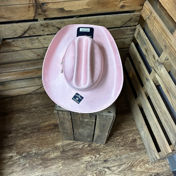 Pink cowboy hat on a wooden block with a rustic wooden background