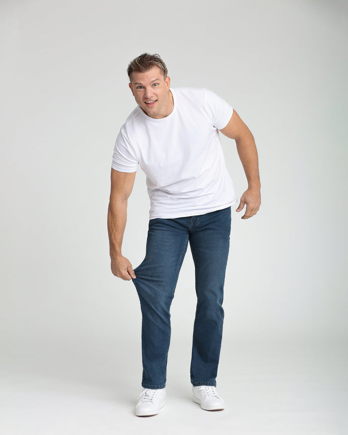 Man wearing white short-sleeve t-shirt and dark blue jeans with white sneakers.