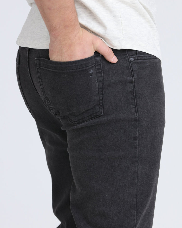 Faded black athletic fit jeans with hand in front pocket, worn with light gray t-shirt.