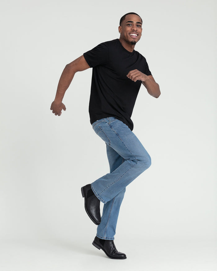 Man wearing light indigo bootcut jeans with black t-shirt and black boots.