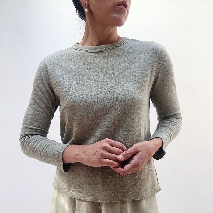 Close front view of model wearing North Star Base artichoke crop double cotton tee, showing raw-edge crew neckline detail, textured fabric, and cropped length