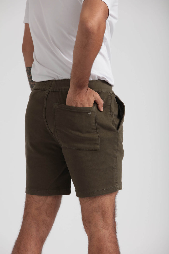 Man wearing olive green slim fit shorts with front pocket and white t-shirt.