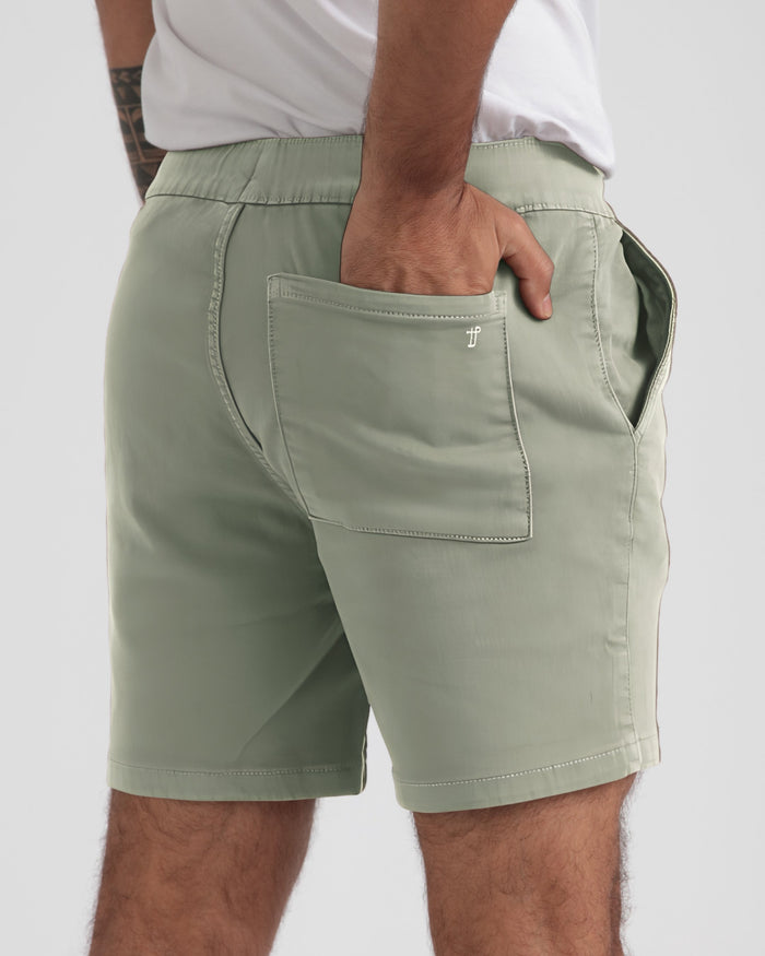Sage green slim fit shorts with elastic waistband and back pocket, worn with white t-shirt.