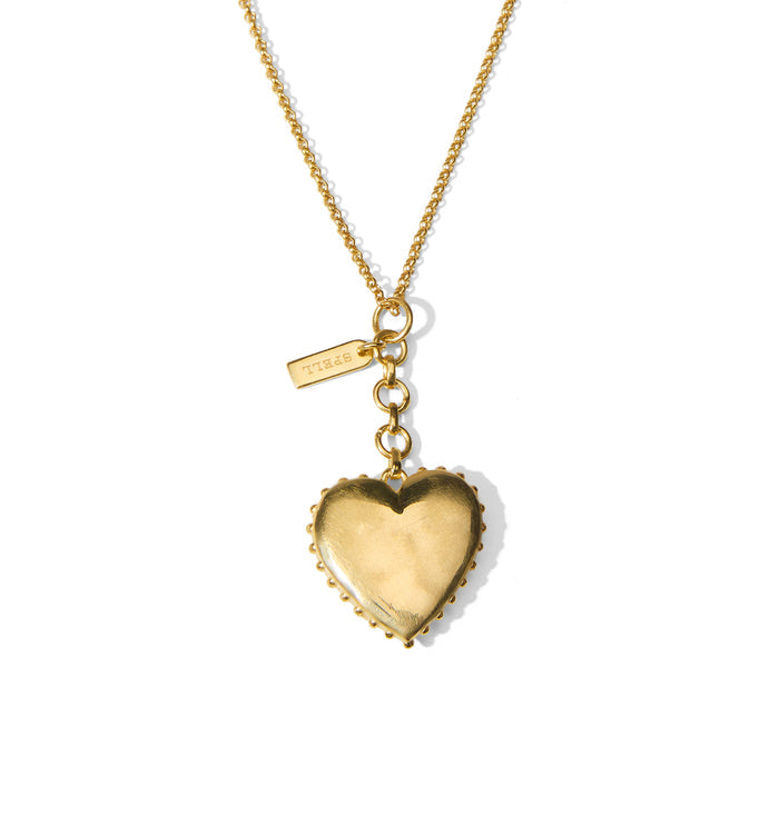 Back view of gold-plated brass heart pendant with beaded border detailing on fine curb chain, Spell charm tag visible