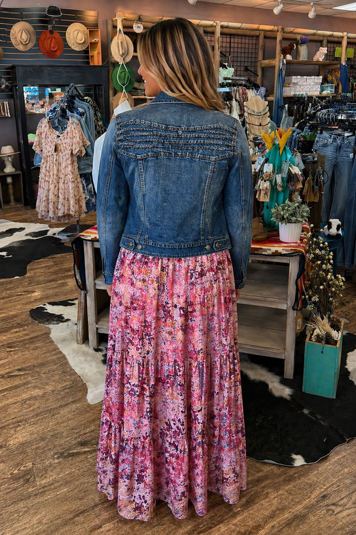 Woman wearing a denim jacket and pink floral dress in a store setting