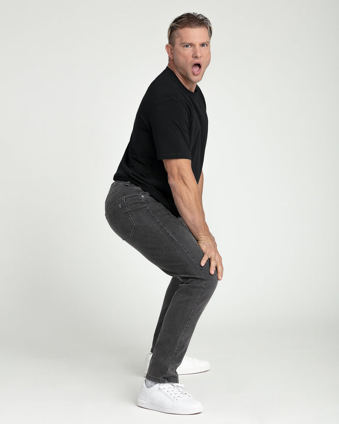 Man wearing black crew neck short-sleeve t-shirt with gray jeans and white sneakers.