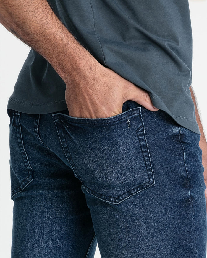 Man wearing slate gray crew neck t-shirt tucked into dark blue jeans, showing fit and fabric texture.