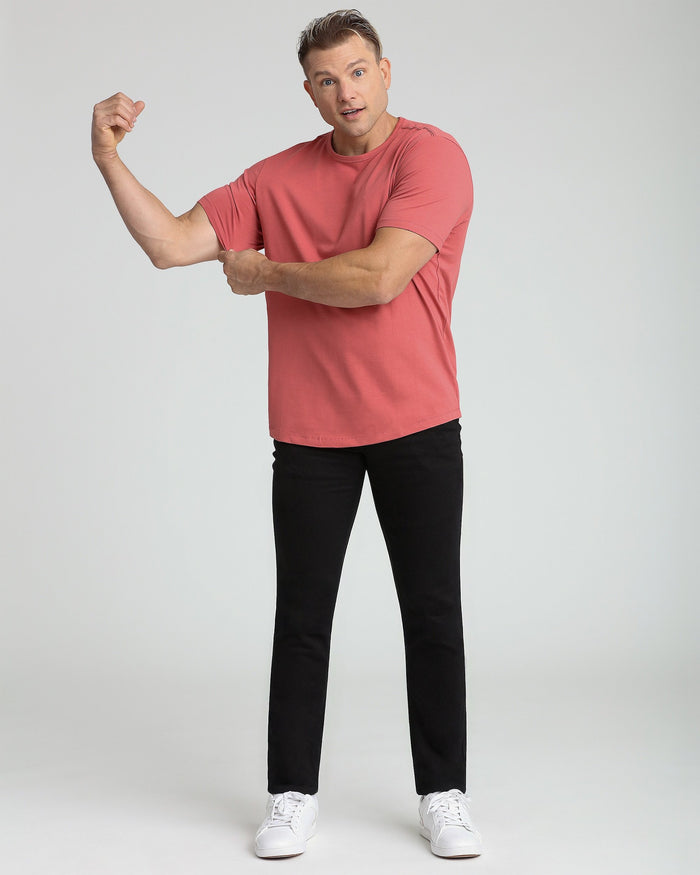 Man wearing coral-red crew neck t-shirt with black pants and white sneakers.