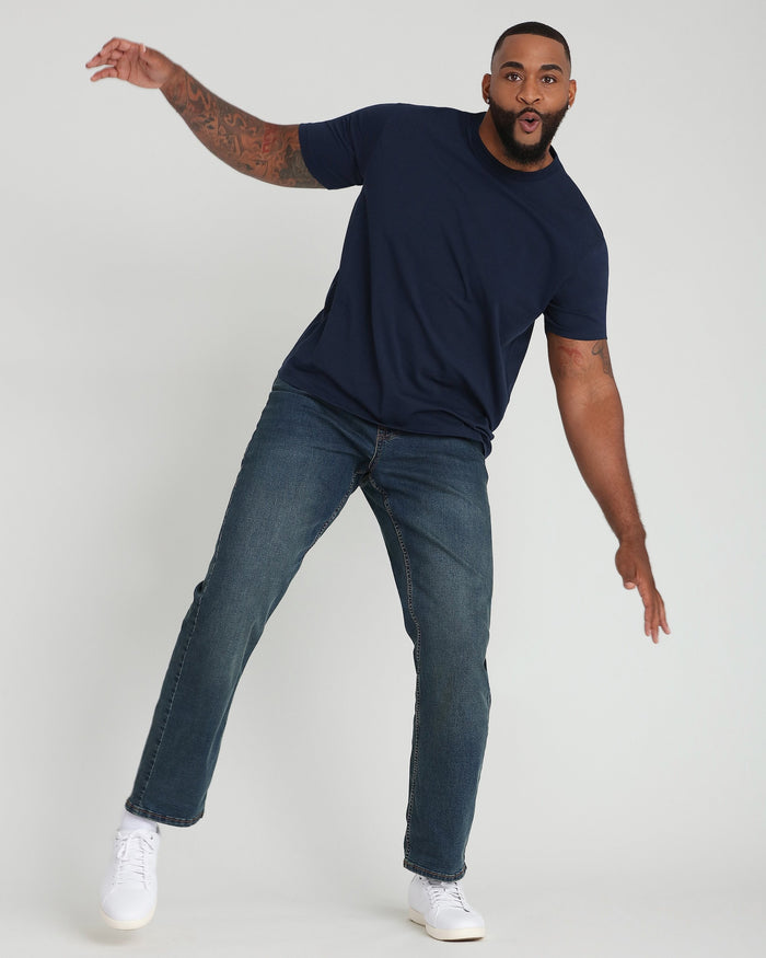 Navy crew neck t-shirt with short sleeves on model wearing jeans and white sneakers.