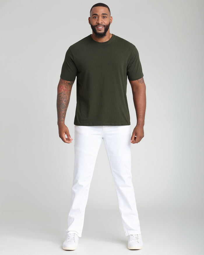 Man wearing olive crew neck t-shirt with white pants and white sneakers.
