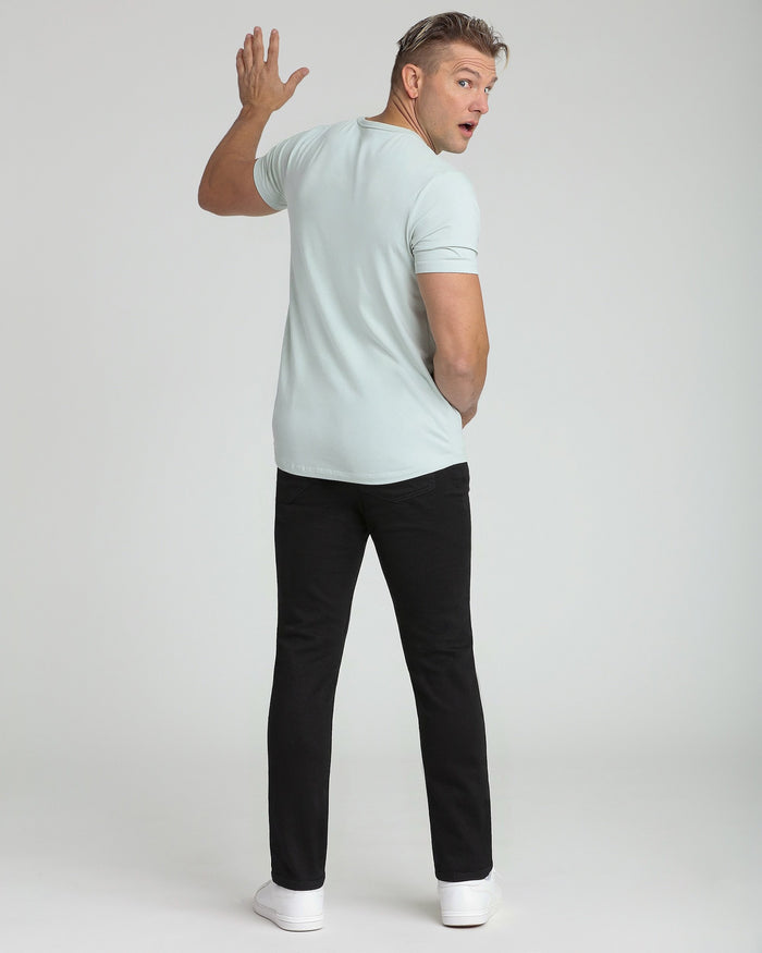 Man wearing light mint crew neck t-shirt with short sleeves and black pants, shown from back view.