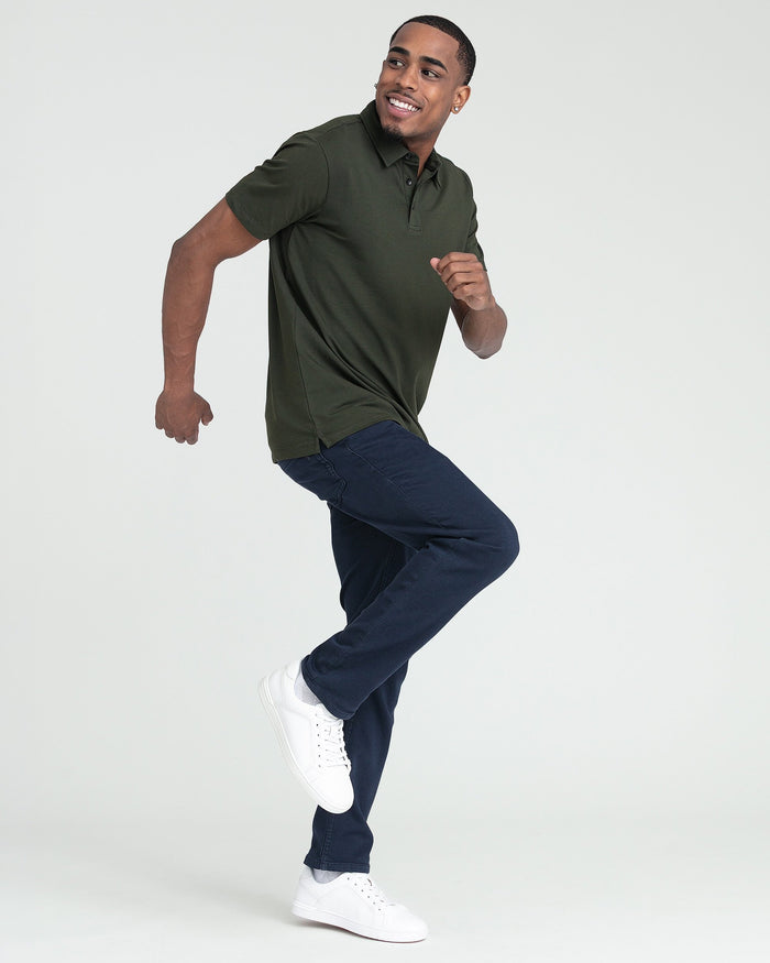 Man wearing olive green short-sleeve polo shirt with dark navy jeans and white sneakers.
