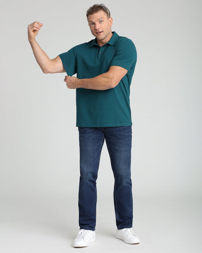 Man wearing teal short-sleeve polo shirt with dark jeans and white sneakers.