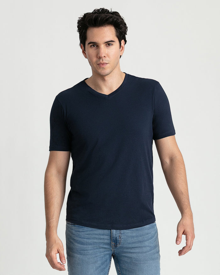Man wearing navy v-neck t-shirt with short sleeves and light blue jeans.