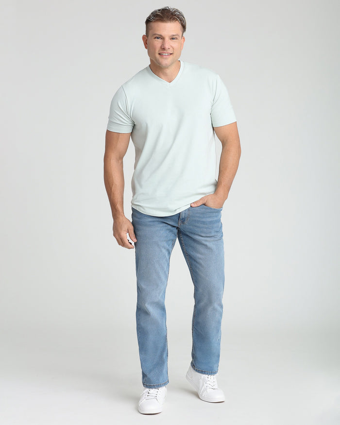 Man wearing light mint V-neck short-sleeve t-shirt with blue jeans and white sneakers.