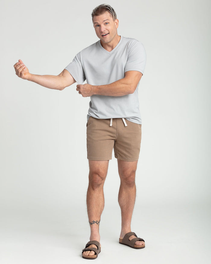 Light grey v-neck t-shirt worn by male model with tan shorts and sandals.