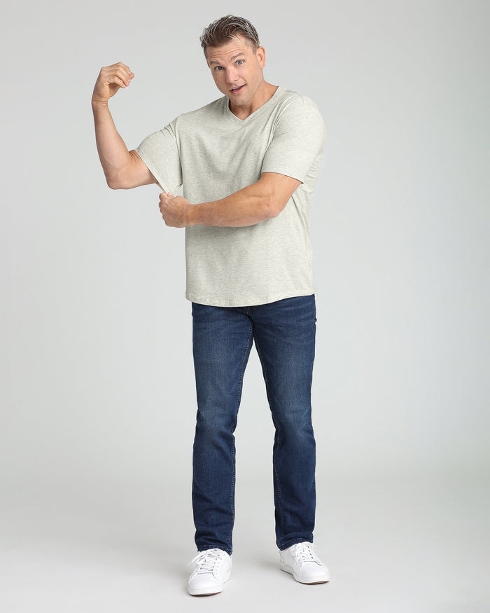 Man wearing oatmeal heather V-neck t-shirt with dark jeans and white sneakers.
