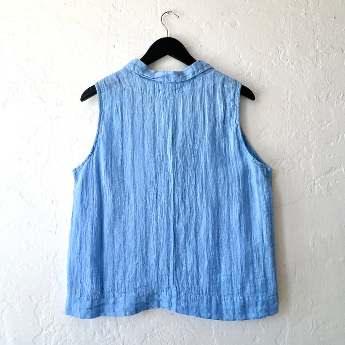 Blue sleeveless top on a hanger against a white wall