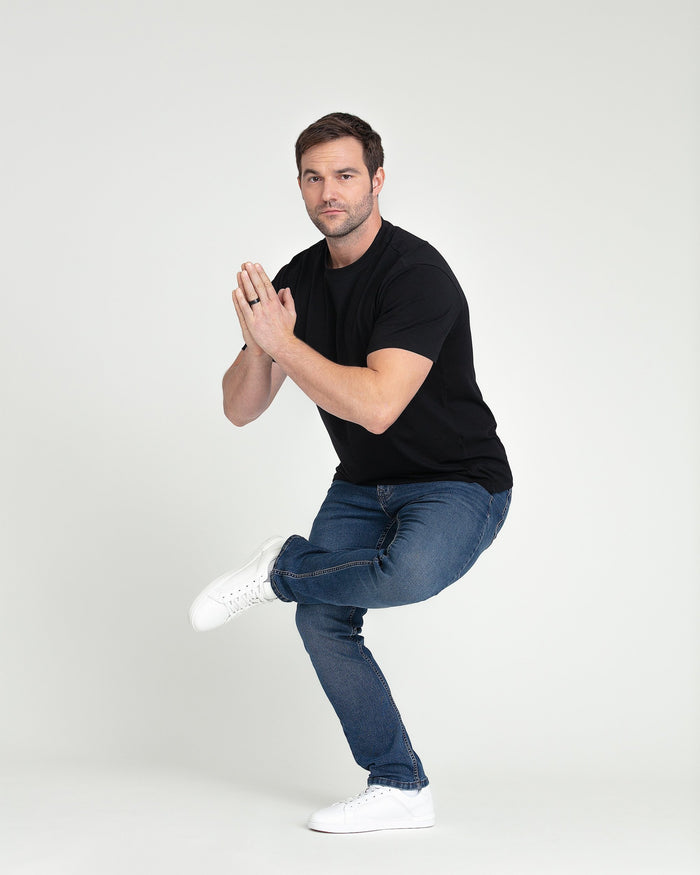 Man wearing black slim fit t-shirt and medium blue jeans with white sneakers.