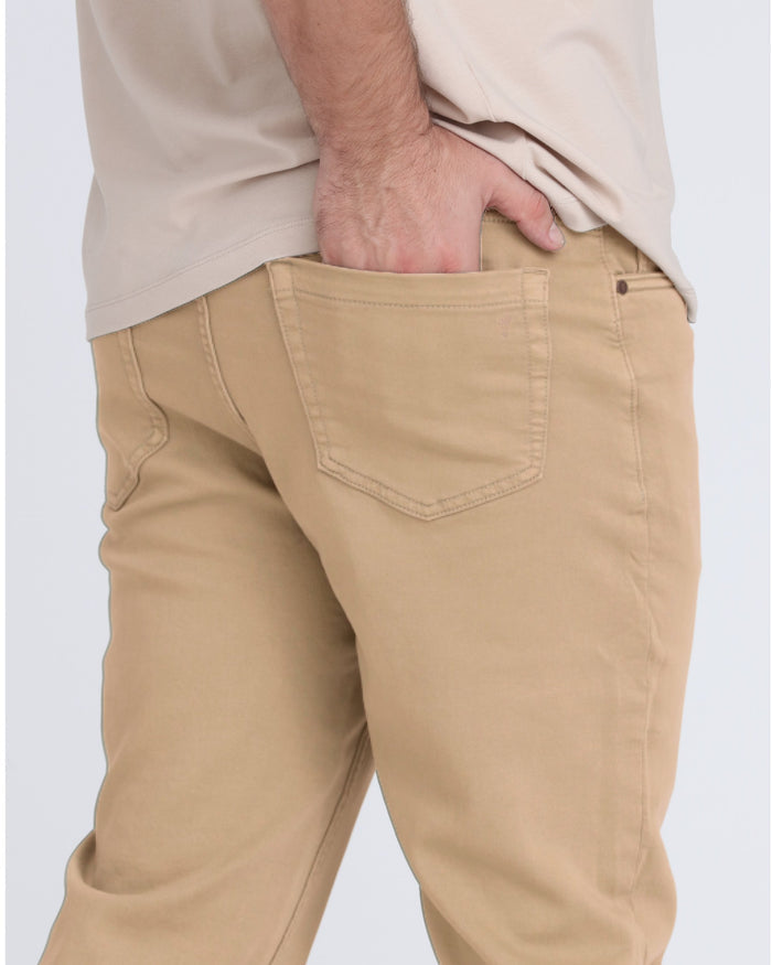 Light khaki slim fit pants with back pocket detail, worn with cream long-sleeve shirt.