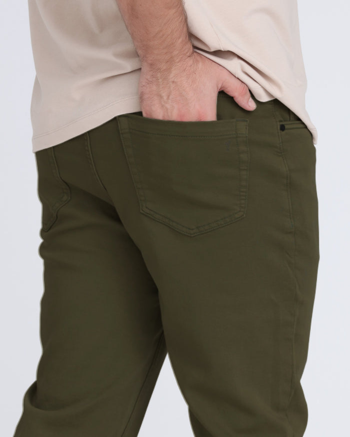 Olive green slim fit pants with back pocket detail, worn with cream shirt.