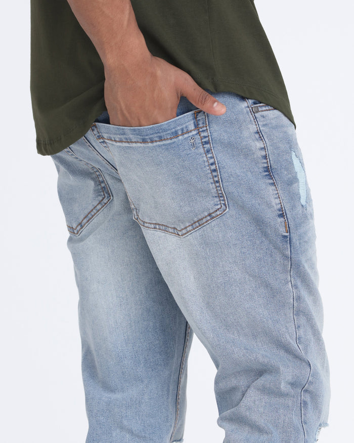 Light wash slim fit jeans with ripped details on the thigh and pocket area.