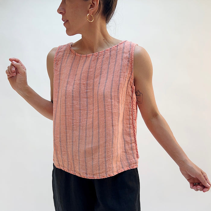 Person wearing a pink striped sleeveless top against a white background, viewed from the front