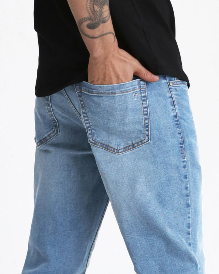 Light indigo denim jeans with relaxed fit, visible back pocket and center seam on model wearing black shirt.