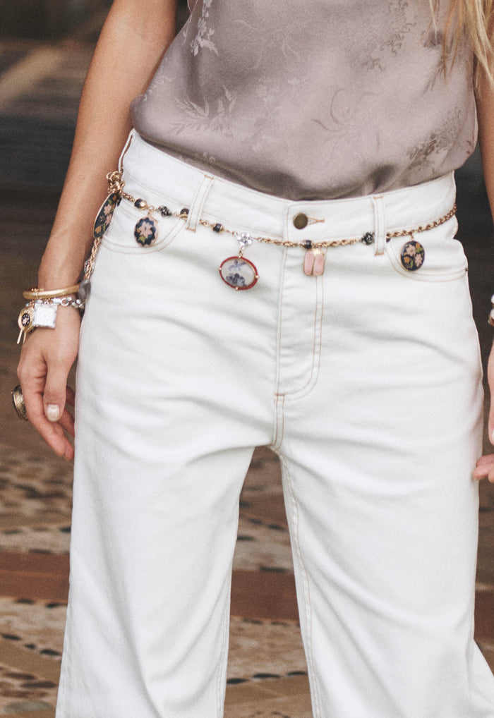 Close-up of salt white organic cotton baggy jeans with gold charm chain belt and contrast stitching