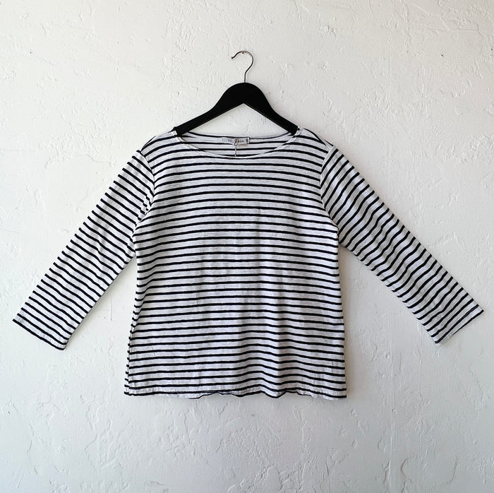 Navy and white striped long-sleeve shirt on a hanger against a white wall