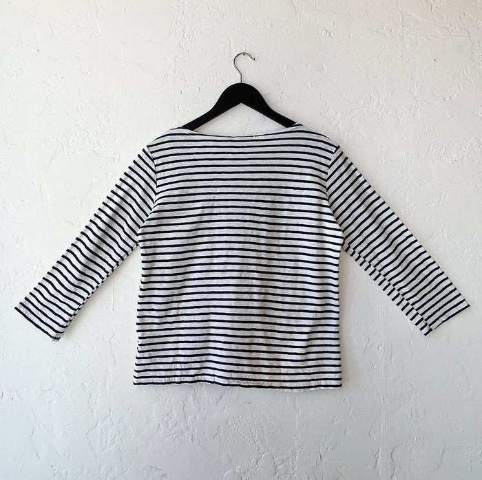 Navy and white striped shirt on a hanger against a white wall, viewed from the back