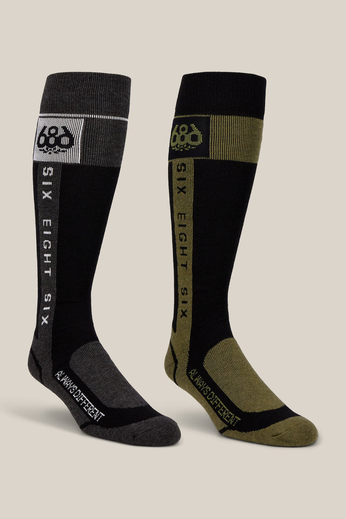 Experience comfort and style with the 686 Men’s Merino Flow Sock 2-Pack. This set includes two knee-high performance socks—one in black and gray, the other in black and olive green—each featuring bold SIX EIGHT SIX and A WHOLE DIFFERENT text printed down the side. Crafted by 686 with quality materials for long-lasting wear, these acrylic men’s socks deliver enduring comfort with every step.