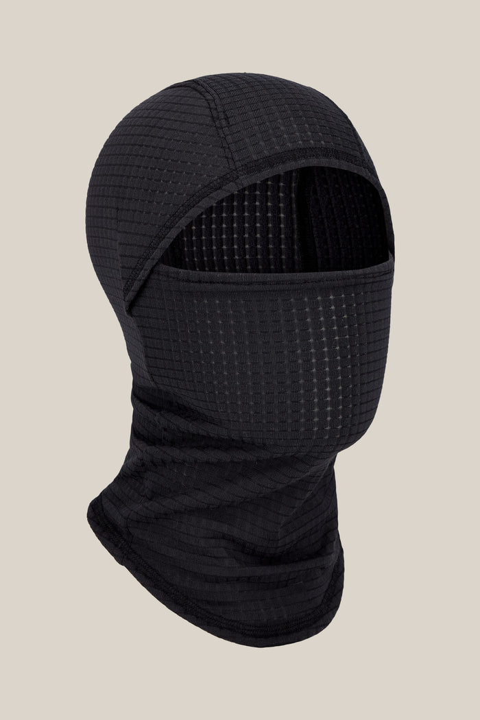 The 686 Mission Grid™ Balaclava by 686 is a black, textured knit facemask featuring a face opening, shown against a plain beige background.