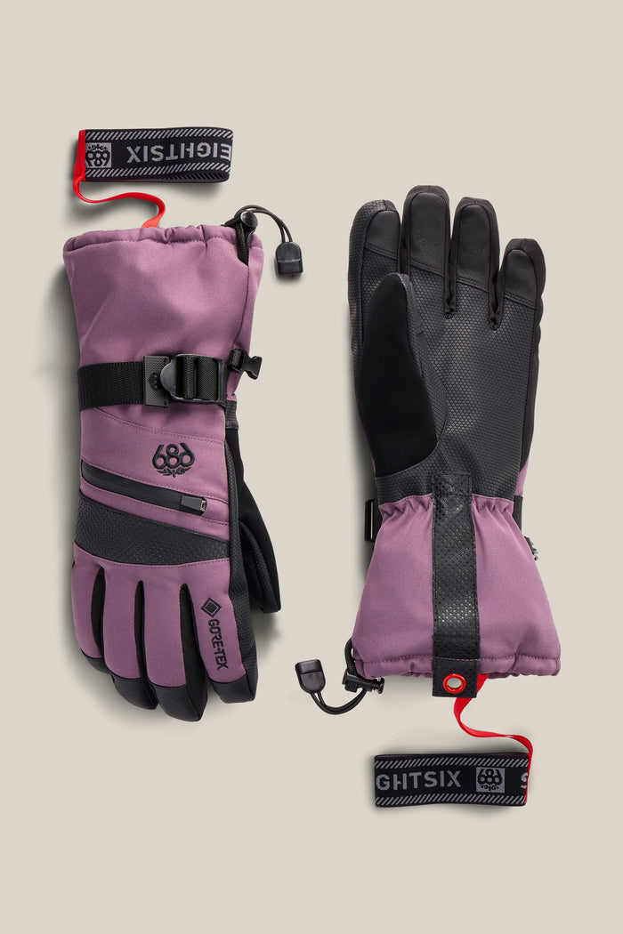 A pair of 686 Women’s GORE-TEX® SMARTY® 3-In-1 Gauntlet Gloves in mauve and black, featuring insulated construction, adjustable cuffs, zippered back pockets, and detachable wrist leashes.