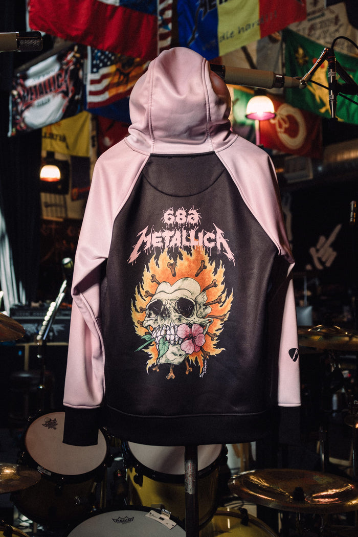 Back view of a black and pale pink 686 Women’s Metallica Bonded Fleece Pullover Hoody featuring a skull graphic surrounded by flames and a flower, with 686 Metallica text above.