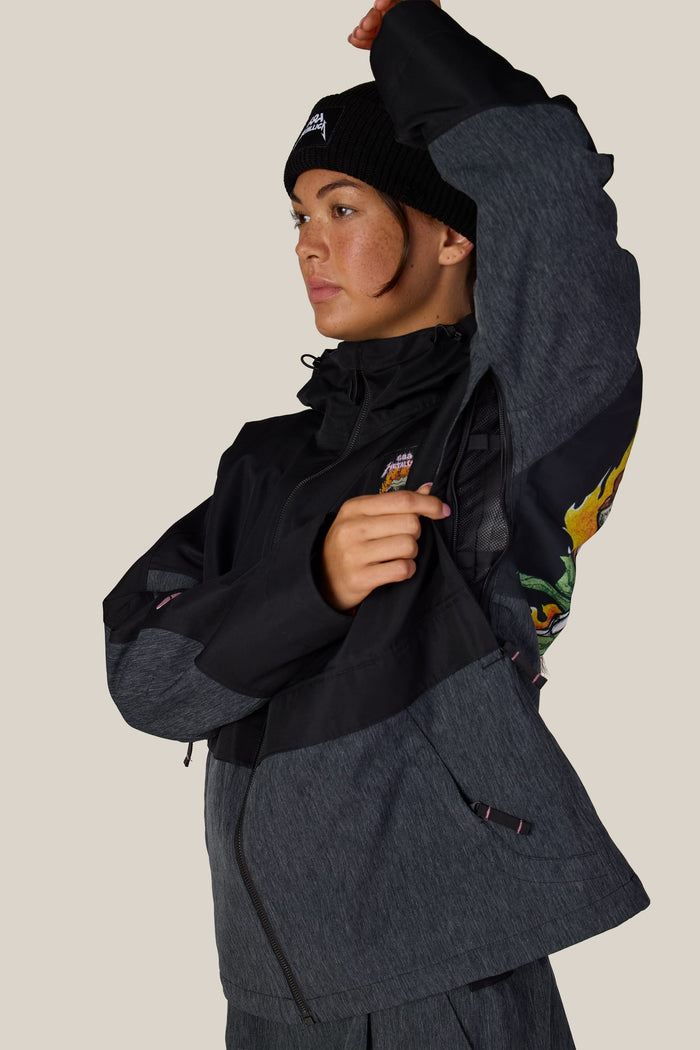 A person wearing a black 686 Women’s Metallica Burning Skull Insulated Jacket, opening a mesh-lined underarm vent.