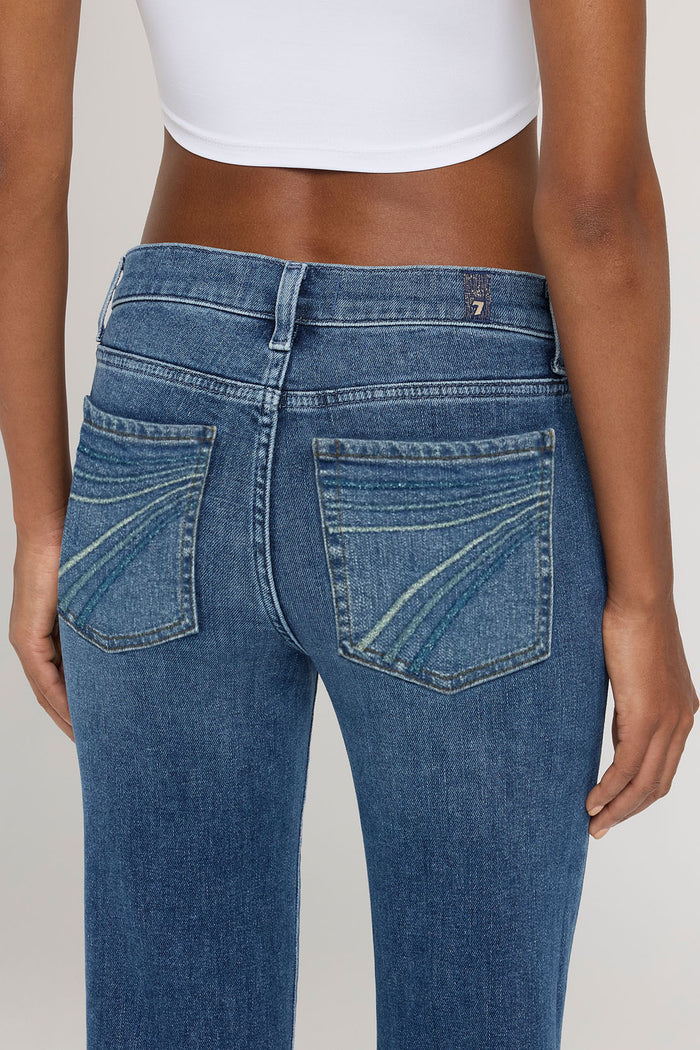 Person wearing blue jeans and a white top on a plain background
