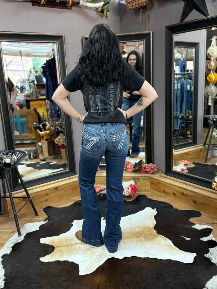 Person wearing a black t-shirt and blue jeans standing on a cowhide rug in a store setting.