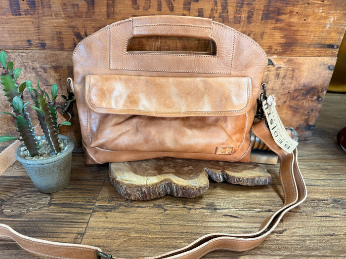 Tan leather satchel bag with top handle, front pocket, and adjustable crossbody strap