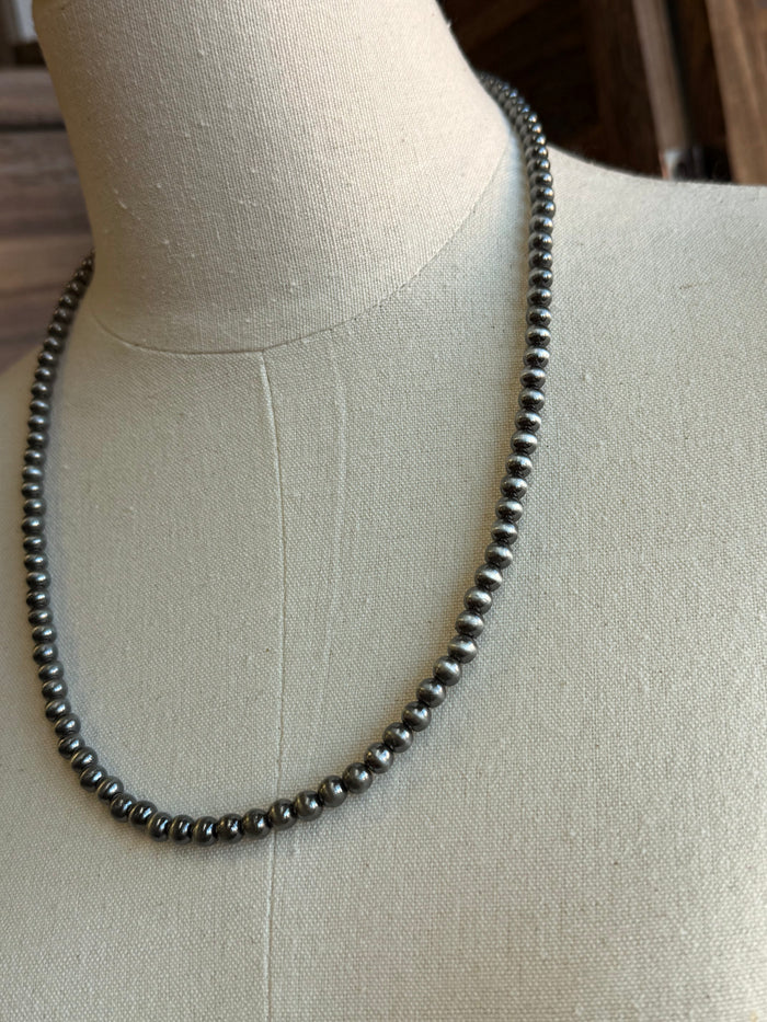 Close-up silver-tone round bead necklace links, ball-chain style