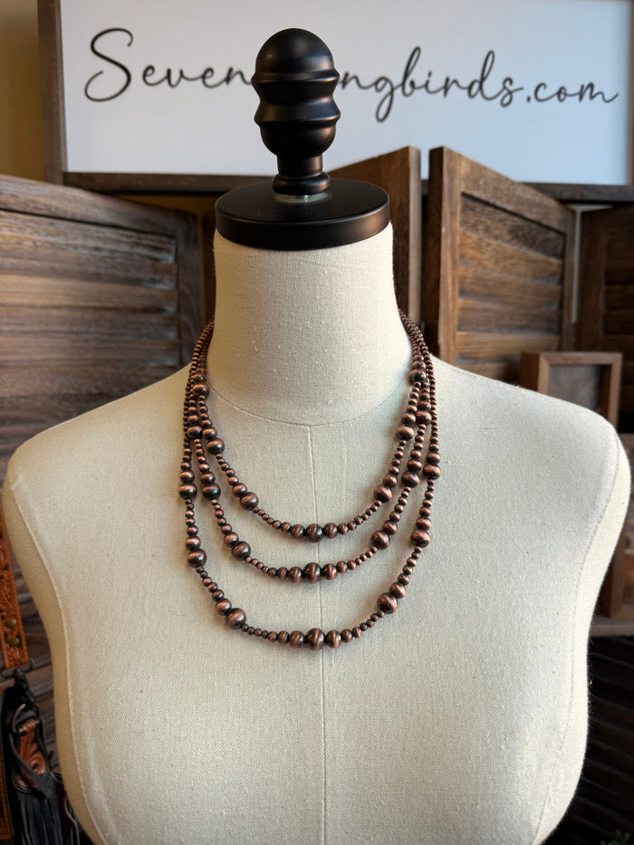 Copper triple-row graduated bead necklace on mannequin, three layered strands with round beads