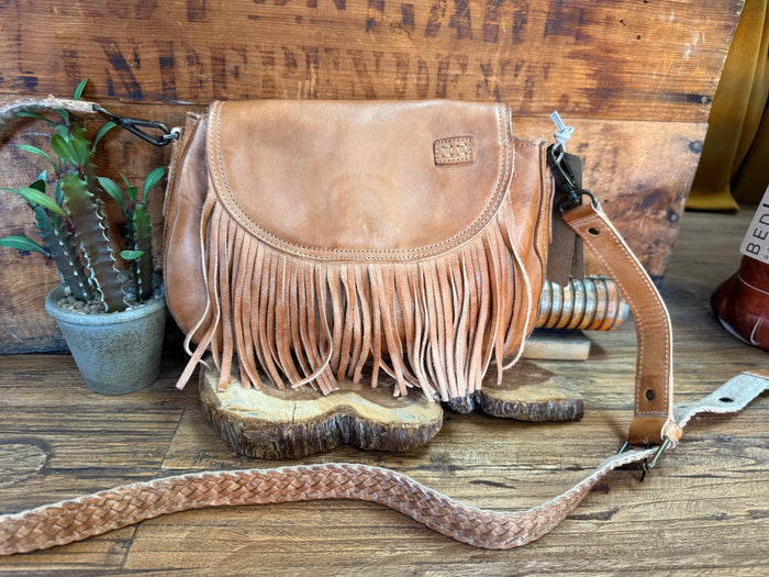Tan suede crossbody fringe bag with flap, decorative stitching, and adjustable strap