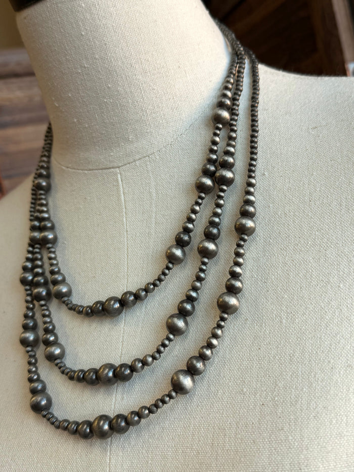 Silver triple-layer graduated bead necklace close-up, showing round bead texture and links