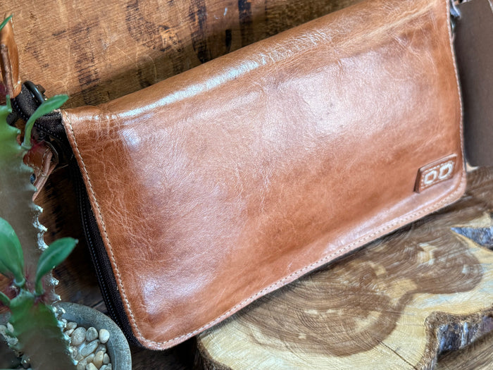 Tan leather flap crossbody bag close-up with buckle and stitched trim