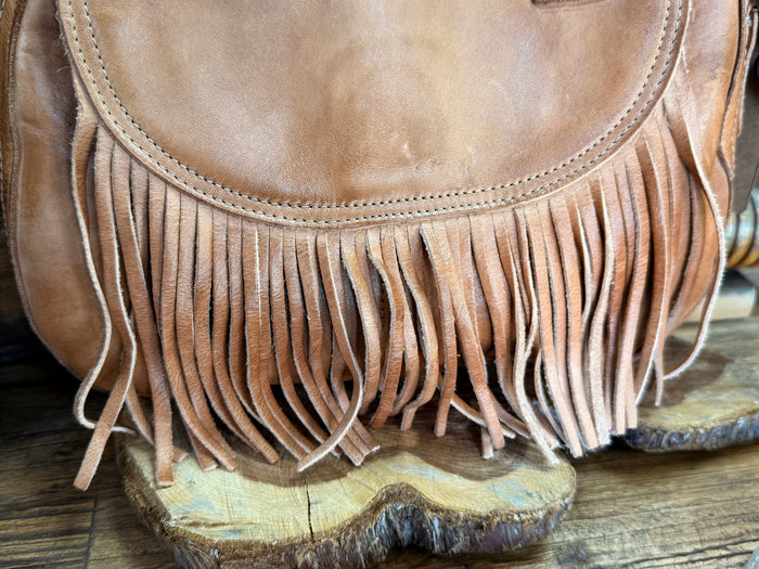 Tan suede fringe bag front close-up with stitched curved flap