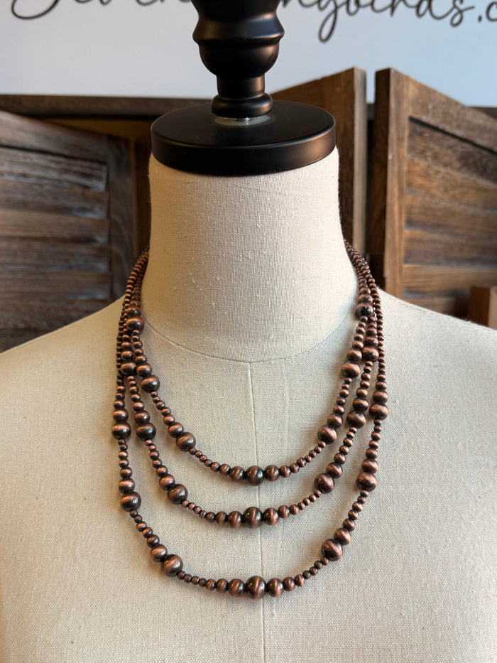 Copper triple-layer graduated bead necklace with rounded beads, layered U-shape