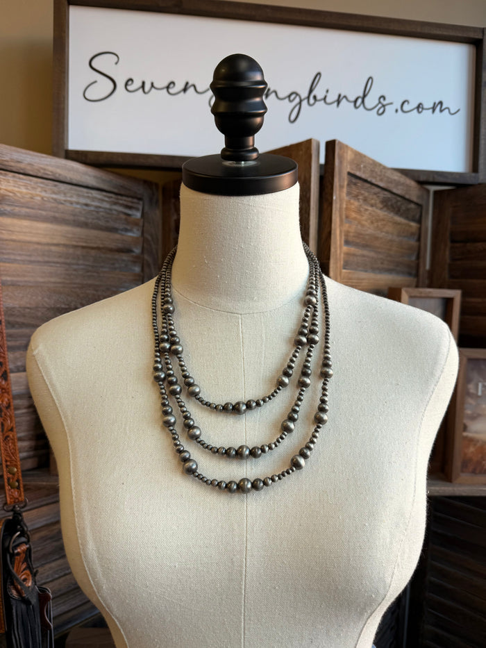 Silver triple-layer graduated bead necklace with rounded bead links, layered U-shape