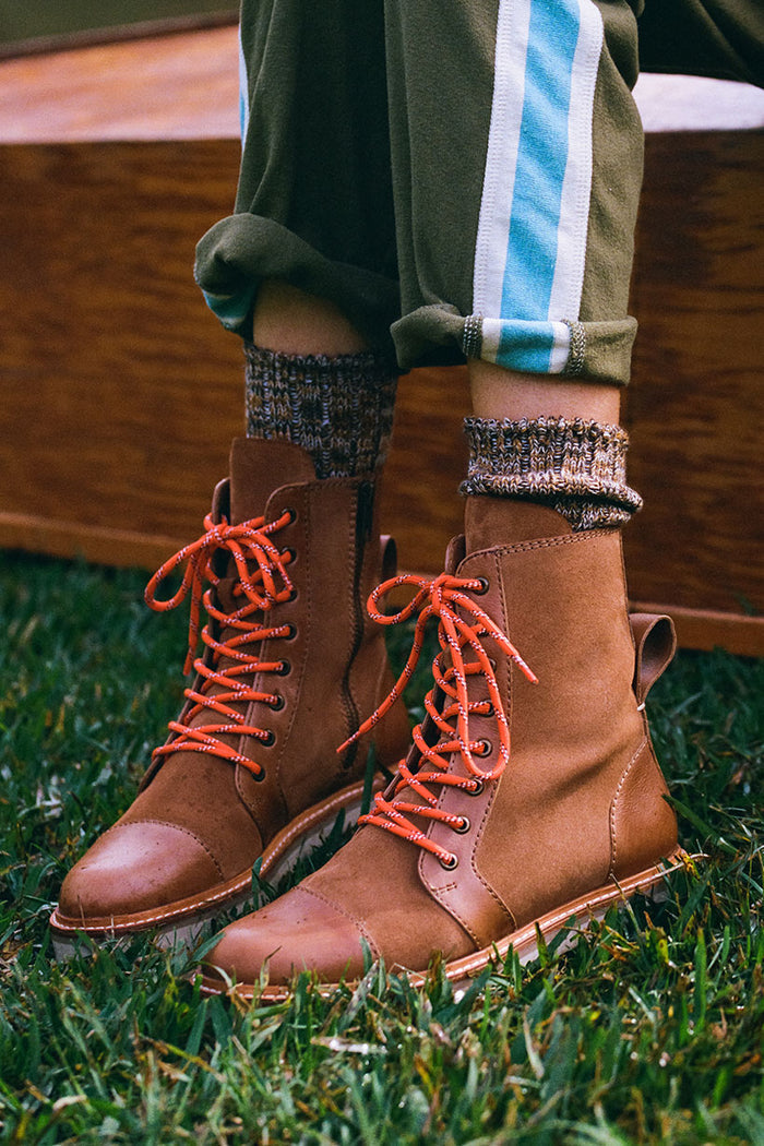 Brown lace-up boots with orange laces worn on grass