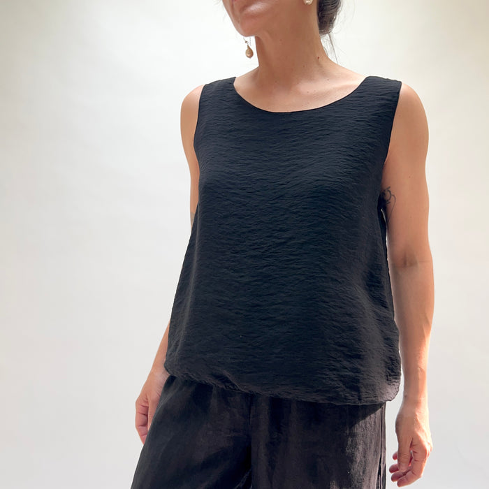 Person wearing a black sleeveless top and pants on a white background