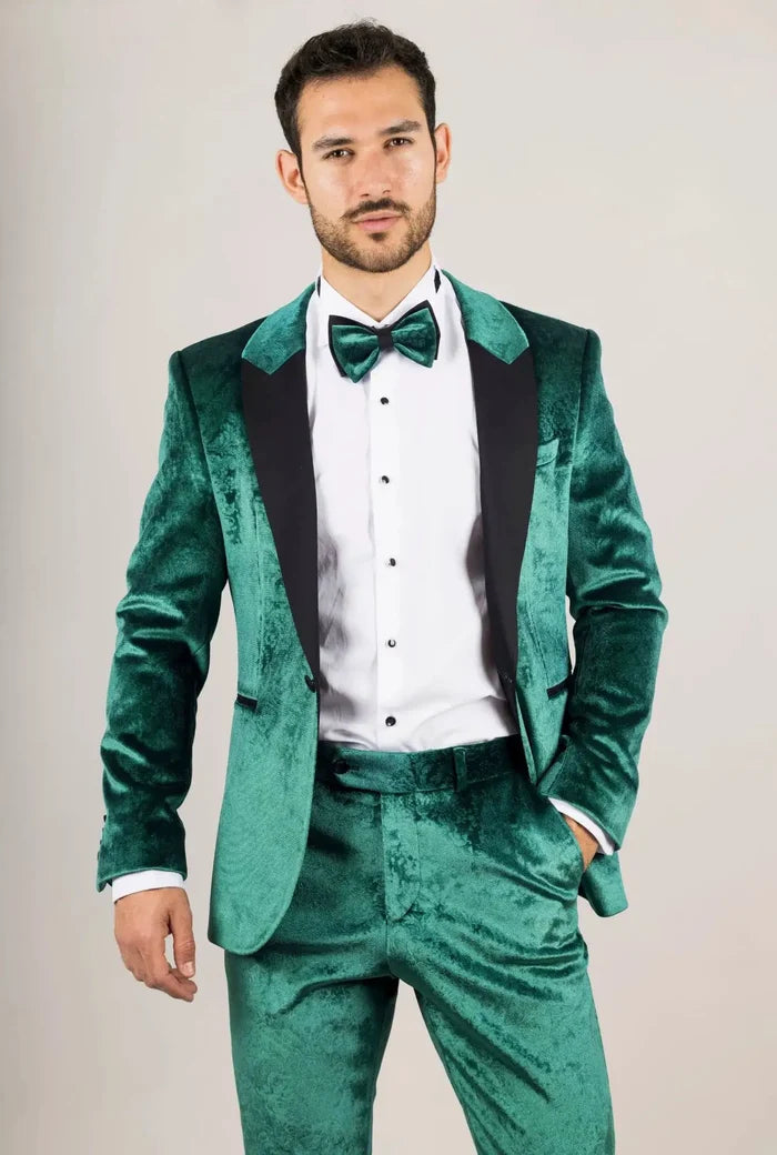 Man wearing a green velvet tuxedo suit with black lapels, matching bow tie, white dress shirt, and black shoes, formal event attire
